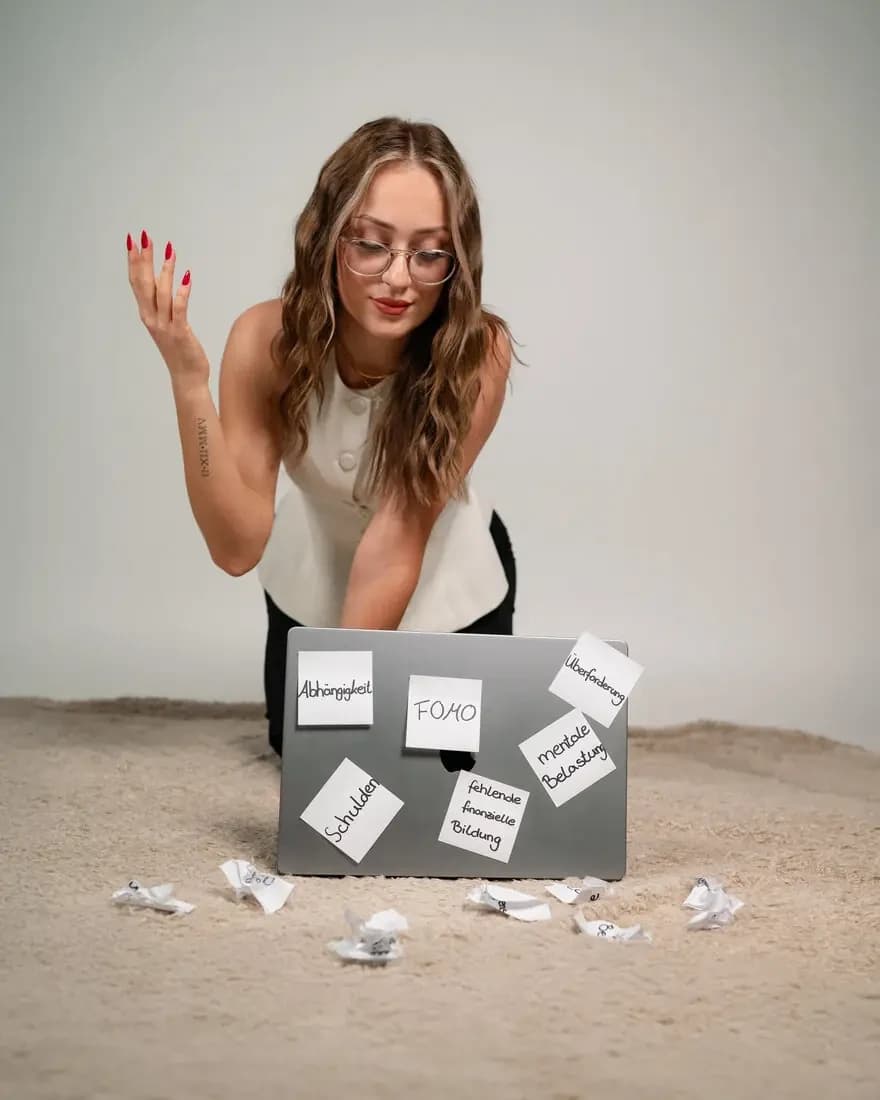 Woman in glasses behind a laptop covered in sticky notes, on sand